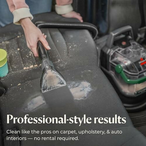 Person using a vacuum cleaner on a car seat for deep cleaning.